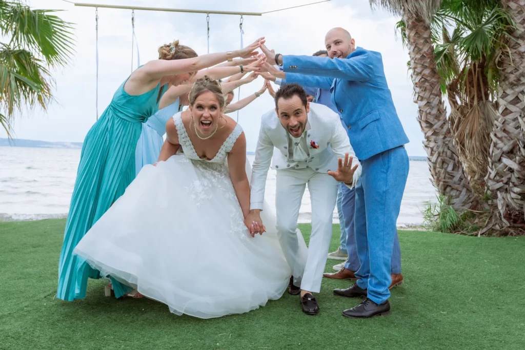 Photographie de mariage de Rebecca et Teddy passant sous une haie d'honneur formée par leurs témoins et demoiselles d'honneur à Rognac
